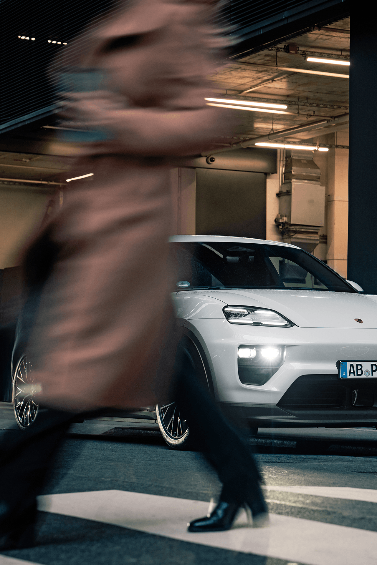 Macan 4 geparkt in einer Tiefgarage. Im Vordergrund eine Person die sich vom Auto wegbewegt.