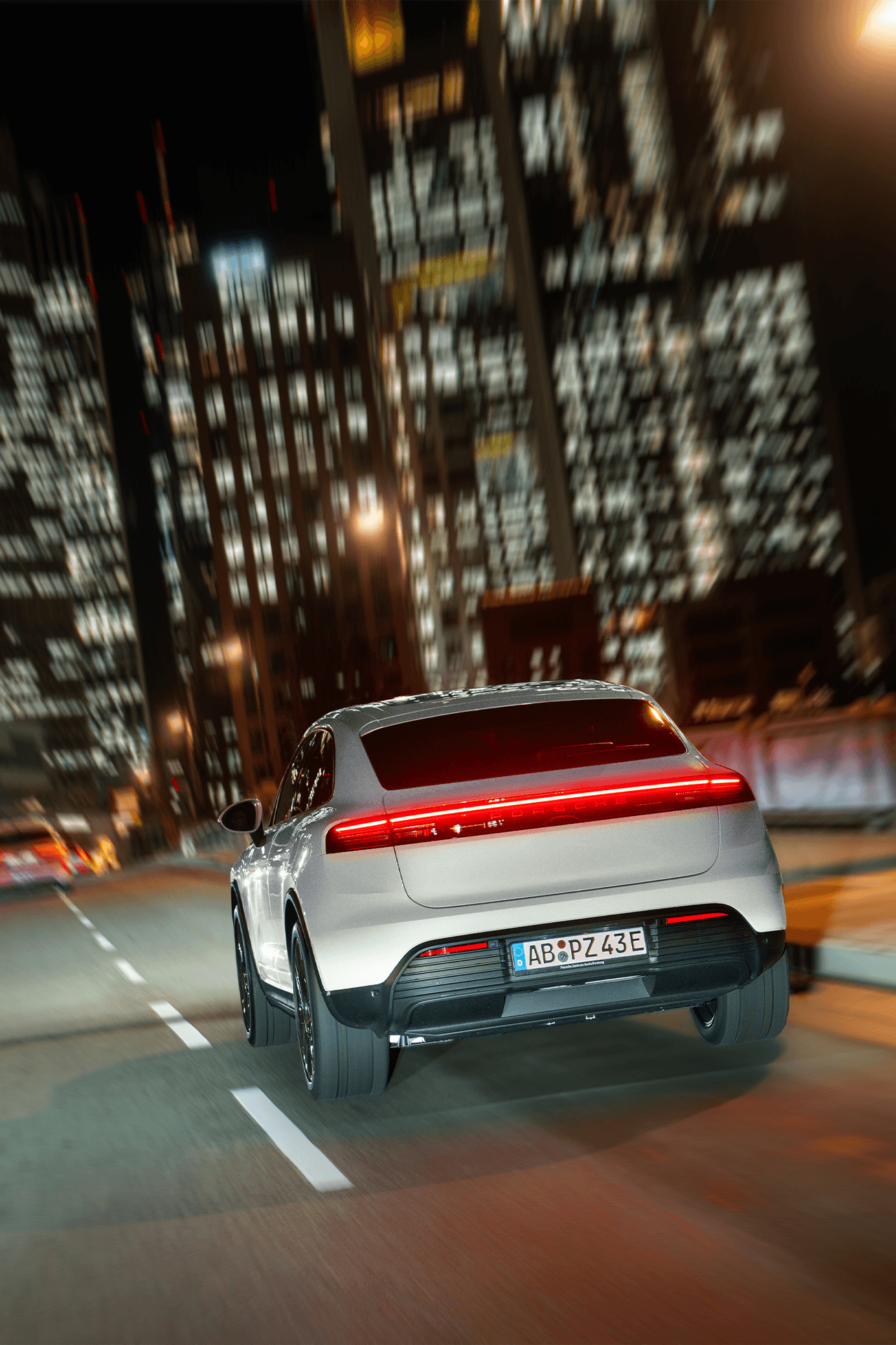 Heckansicht des Macan 4 während der Fahrt durch die nächtliche Stadt
