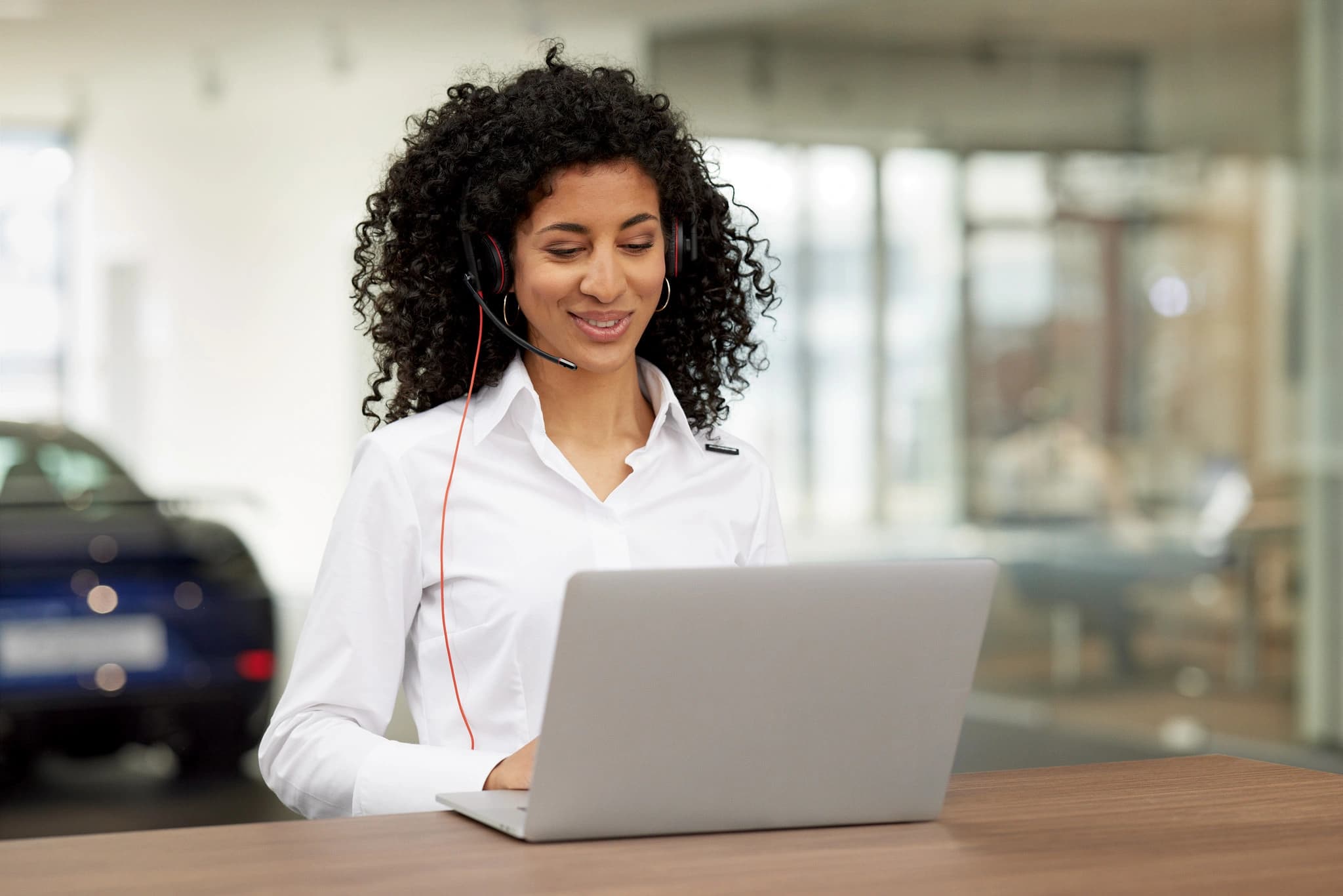 Eine Beraterin sitzt an einem Laptop und telefoniert mit einem Kunden