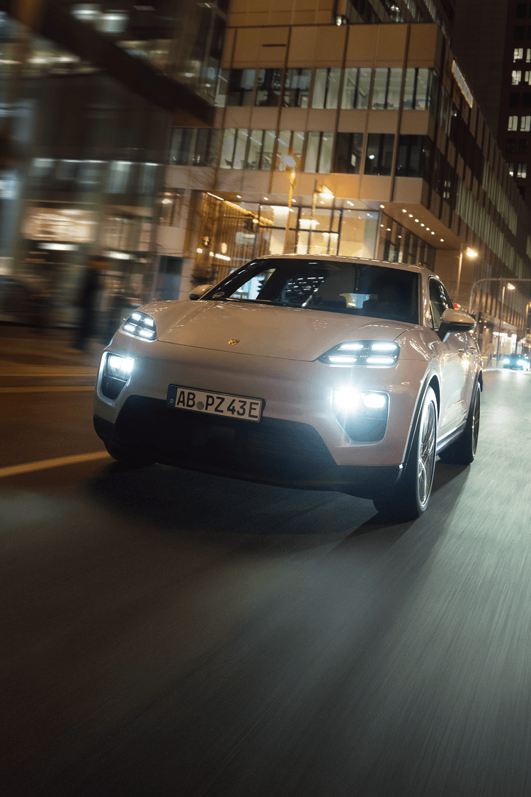 Vorderansicht des Macan 4 während der Fahrt durch die nächtliche Stadt